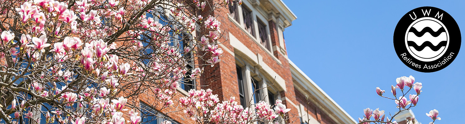 Tree with blossoms stands in front of a UWM building on campus