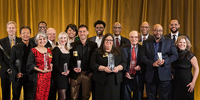 2023 Alumni Awardees pose on stage with UWM leadership members.