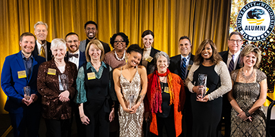 2024 Alumni Awardees pose on stage with UWM leadership members.