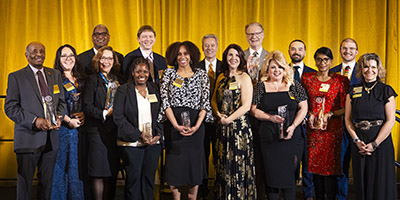 2025 Alumni Awardees pose on stage with UWM leadership members.
