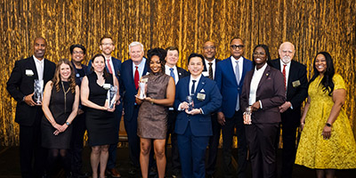 2026 Alumni Awardees pose on stage with UWM leadership members.