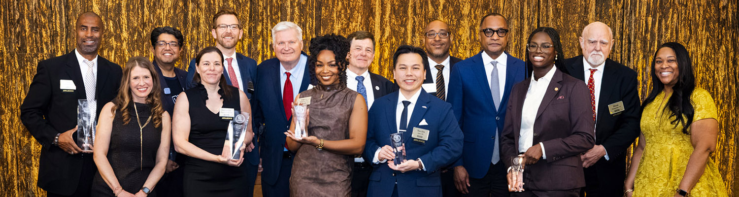 2026 Alumni Awardees, Chancellor Thomas Gibson and UWM staff members pose for a photo on stage.