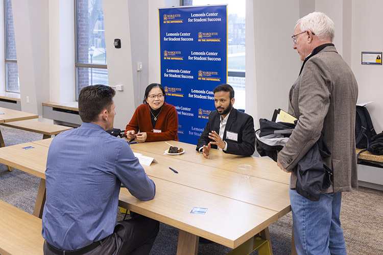 Xiaohua Peng, Taufeeque Ali and two men converse around a table