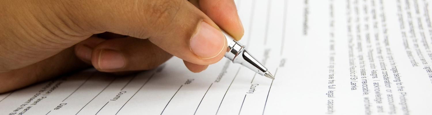 Close-up of a hand filling out a request form with a pen, emphasizing the process of submitting formal applications and documents.