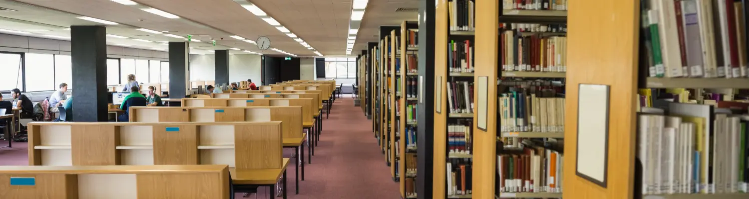 aisle in library; chairs on one side, stacks on the other