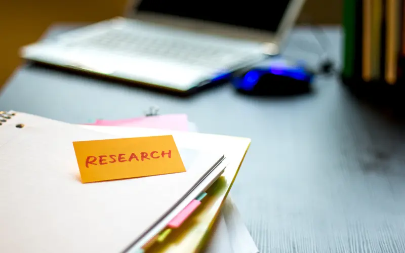 folders on table with a sticky note reading "research"