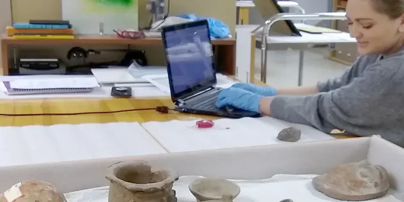 person using laptop while sitting next to museum pieces