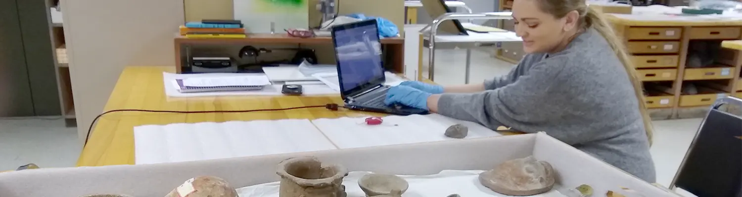 person using laptop while sitting next to museum pieces