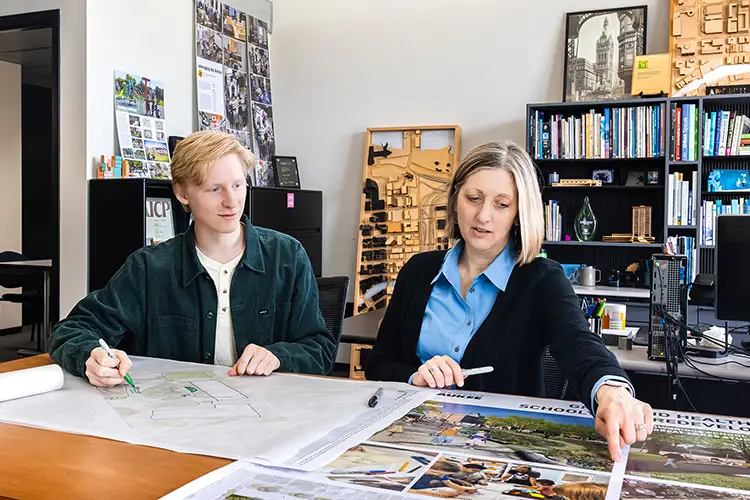 Carolyn Esswein and a student interact while looking at urban planning documents.