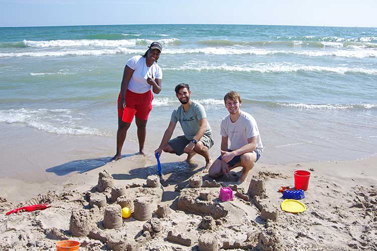 Architecture students build sand castles at the beach as part of their educational and social gatherings.
