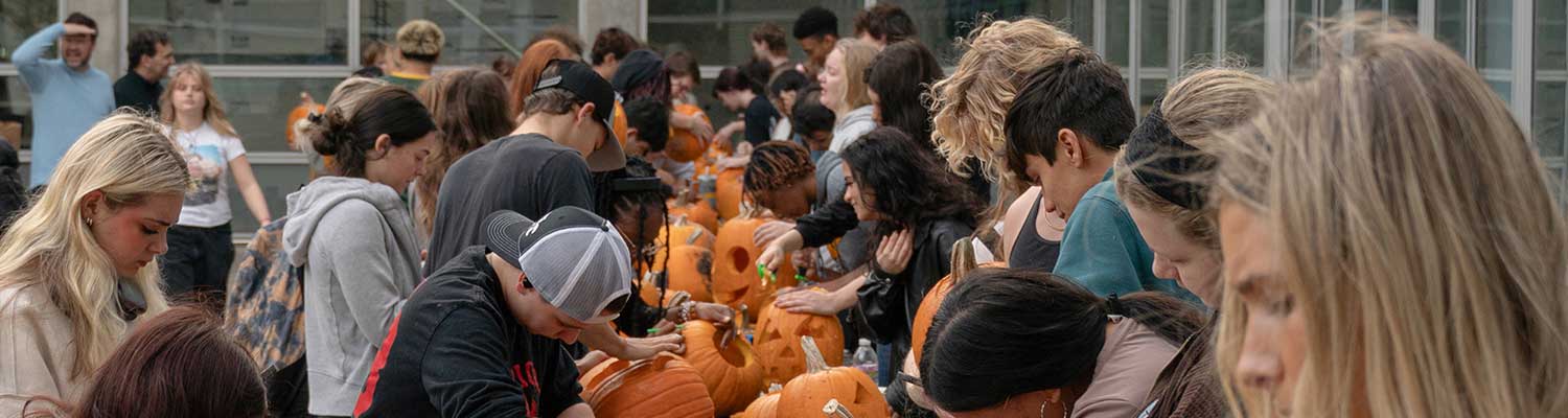 Students carve pumpkins outside in the courtyard of the architecture and urban planning building.