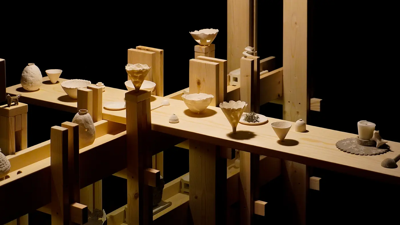 Wooden structure with white ceramic bowls and vases arranged on its beams.