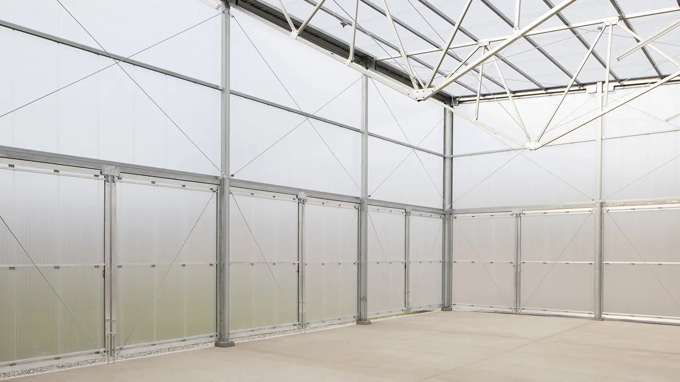 Empty industrial-style room with metal beams, frosted panels, and a concrete floor.