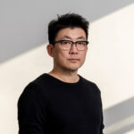 Dong Gong stands with light and shadow behind him.