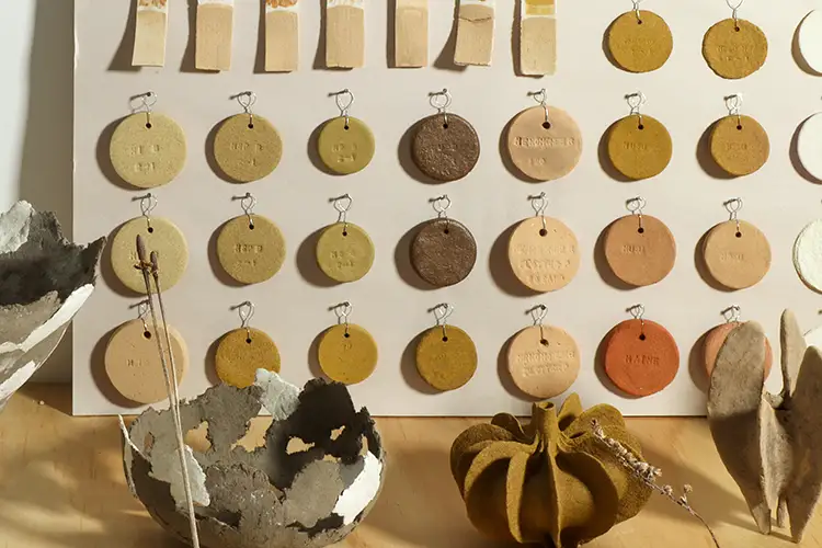 Circular clay forms hang on a board in a neat pattern.