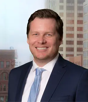 Headshot of Samuel Schultz in front of a city skyline.