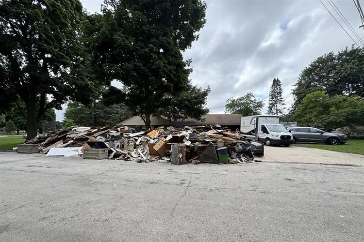 A pile of debris sits on the curb outside of a home.