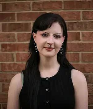 Lindsay Voelsing smiles in front of a brick wall