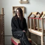 Adrienne Economos-Miller sits in a studio with models surrounding her.
