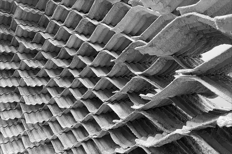 Black and white close-up of layered corrugated panels forming a repeating wavy pattern with rough textures and overlapping edges. Black and white close-up of layered corrugated panels forming a repeating wavy pattern with rough textures and overlapping edges.