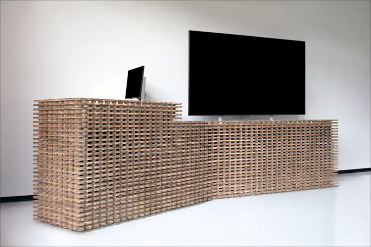 Curved wooden lattice reception desk with a black monitor and large wall-mounted screen in a minimal white room. Curved wooden lattice reception desk with a black monitor and large wall-mounted screen in a minimal white room.