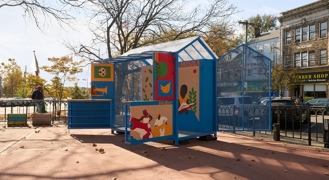 Colorful community market pavilion with illustrated panels in an urban plaza.