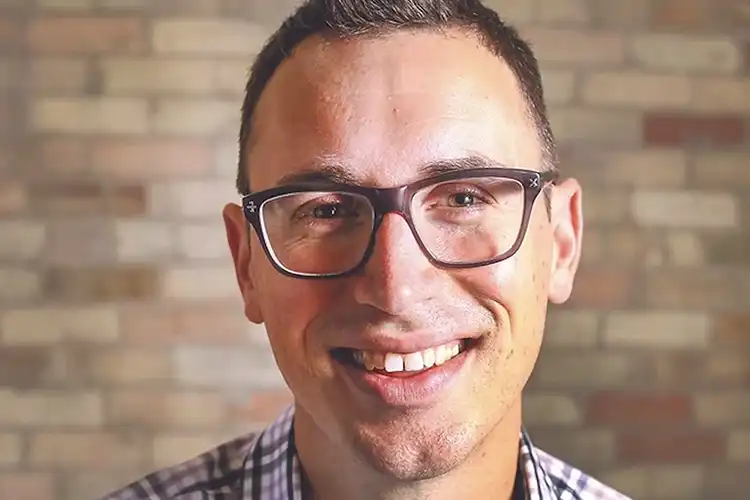 Headshot of Piotrowski. He's wearing glasses and a blue and white striped shirt.