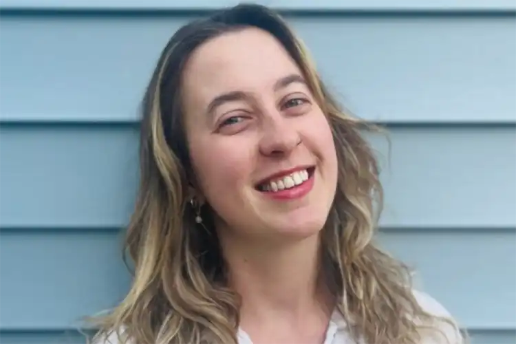 McGinnis' headshot. She smiles in front of a light green wall.