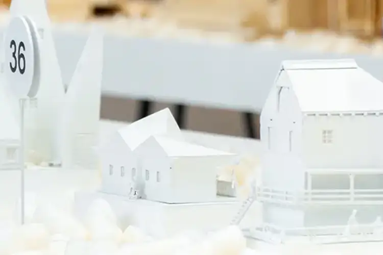 Architectural scale models and a numbered marker displayed on a tabletop during a design review or exhibit.