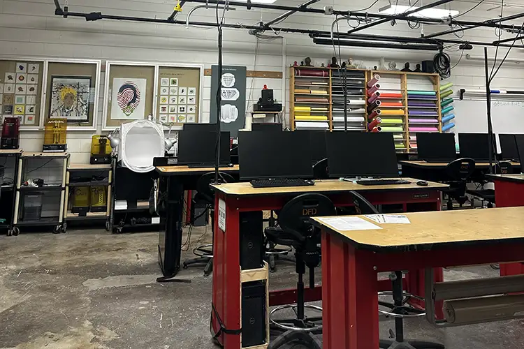 Spacious lab with workstations, 3D printing and fabrication equipment, and colorful material storage.