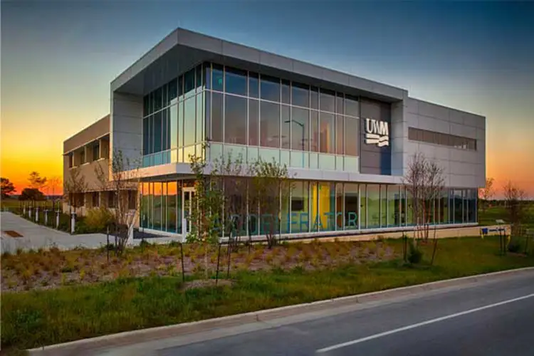 Modern glass-front university innovation building at sunset.