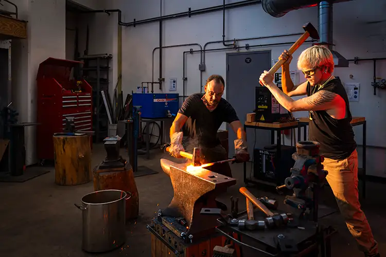 Faculty Adam Hawk and undergraduate Cole Lehto work on metalsmithing research.