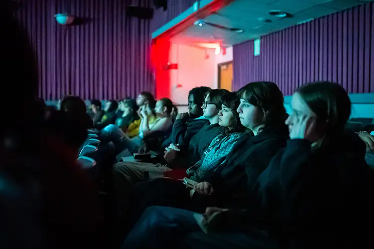 Students attend Experimental Tuesdays and are seen in the dimly lit UWM Union Cinema.