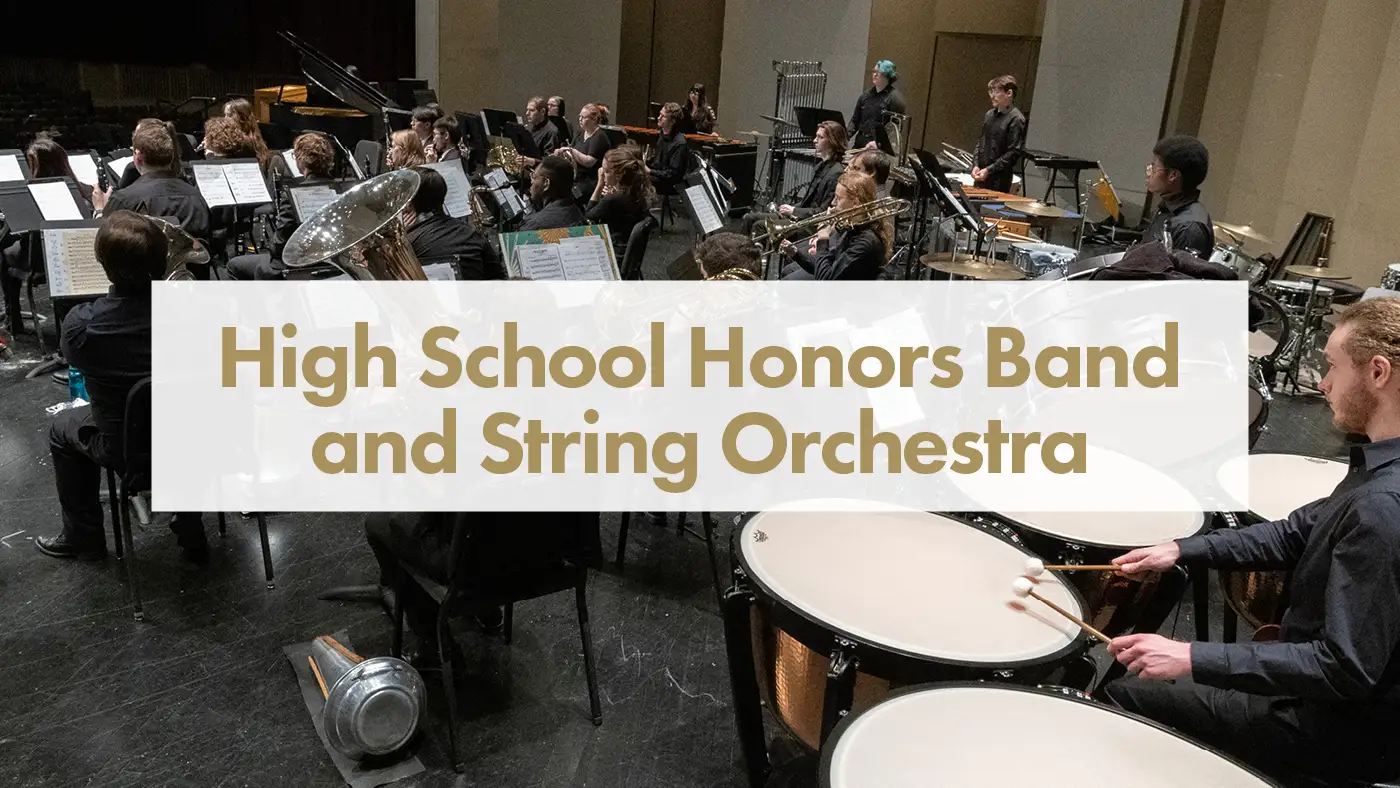 Students perform on stage with wind and percussion instruments.