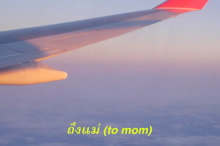 A plane wing sits slanted in front of a pink, purple, and blue sunset. Yellow subtitles feature the Thai term for "to mom".