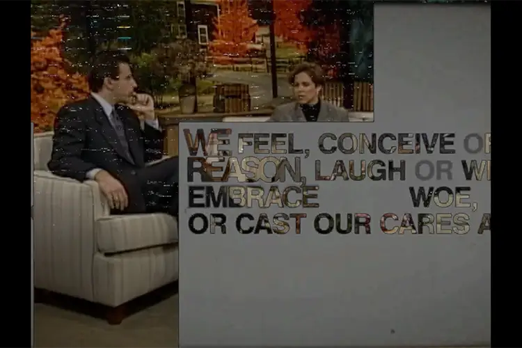 Two people seated in a studio set with autumn scenery, partially obscured by large overlaid text fragments on the screen.