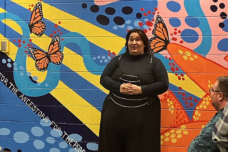 Sav Canales stands in front of her mural.