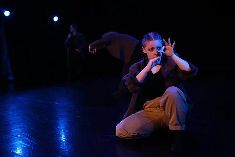 Syd Bannach gestures OK in a dance number on a dimly lit stage.