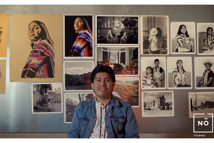 Jovanny poses in front of his photography on display