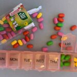 Colored candies and a weekly pill organizer are displayed on a grey surface. They are items used in Care Shower games.