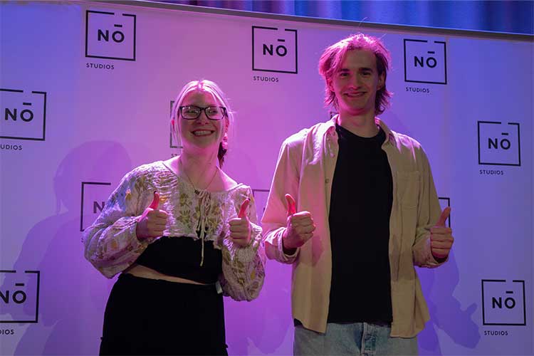 Two students pose in front of a No Studios banner at the Filmmaker Showcase.