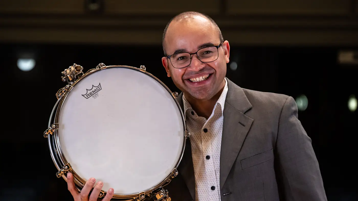 A close up of Jean Carlo Ureña Gonzalez holding a gold rimmed snare drum.