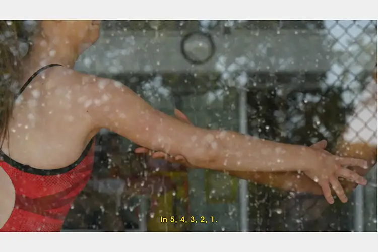 Film still of woman's arm being held by someone else seen through a window. Text reading "in 5, 4, 3, 2, 1." Film still of woman's arm being held by someone else seen through a window. Text reading "in 5, 4, 3, 2, 1."