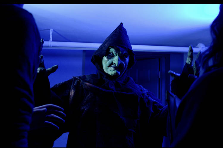 A witch looms over two people