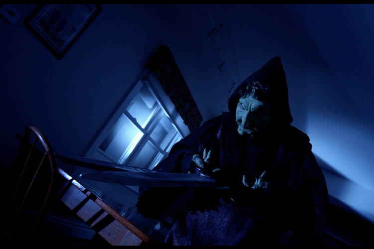 A witch looms to the left of the screen with a large pair of scissors