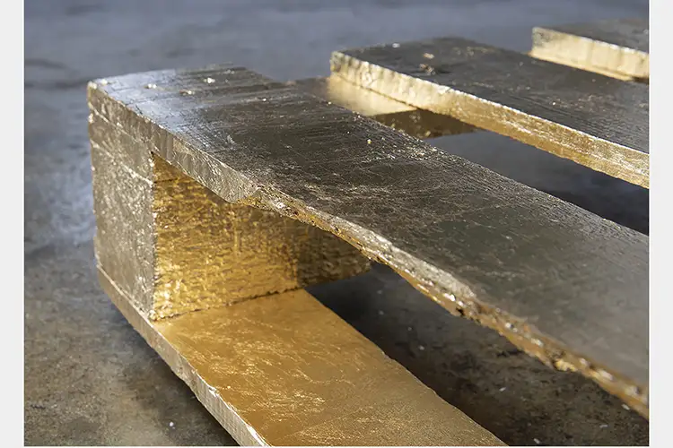 Close up of a corner of wood palette covered in gold leaf
