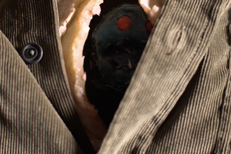 A parasite peaks out between the folds of a mans jacket