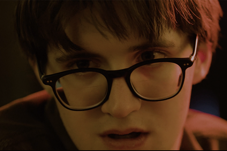 A man looks dramatically to the left while being cast in red and green light