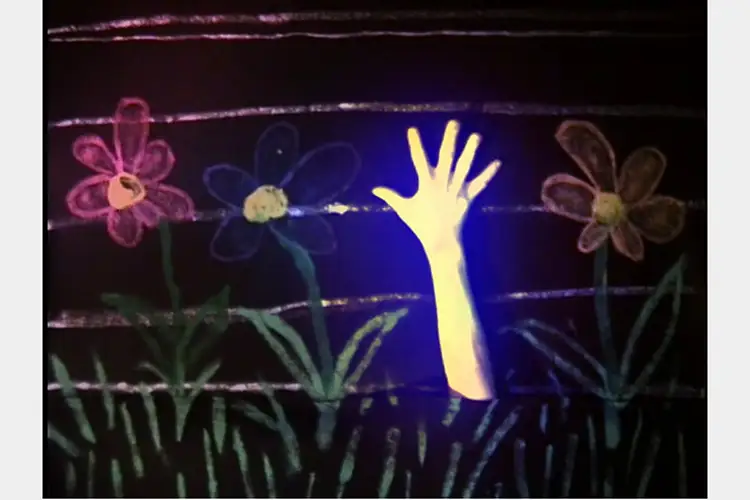 A glowing hand reaching out of the dirt in a drawn row of flowers.