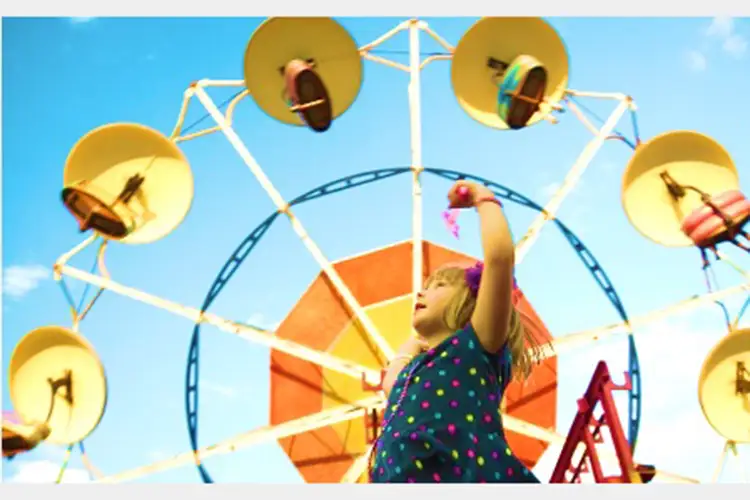 Image looking up at a young girl in motion beneath a carnival ride Image looking up at a young girl in motion beneath a carnival ride